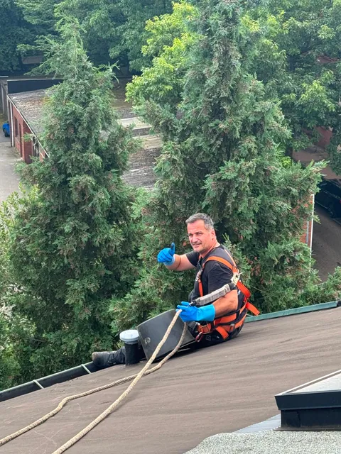 Einsatzfoto von ExpertRinnen: Mitarbeiter mit Sicherheitsgurt und Spülschlauch auf einem Flachdach