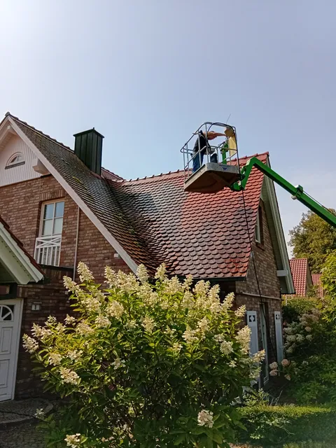 Einsatzfoto von ExpertRinnen: Mitarbeiter im Korb eines Hubsteigers über dem Dach eines Klinkerhauses